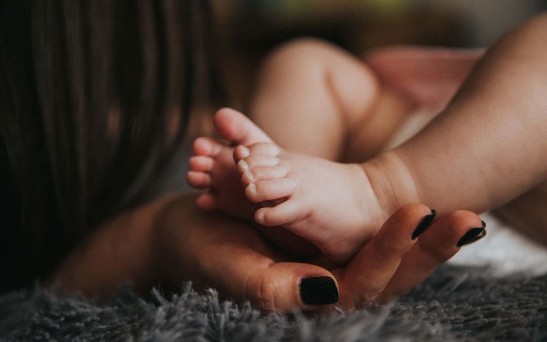 Pies de un bebé en las manos de su mamá